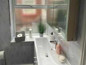 a bathroom with a white sink and a window at New York Apartment in Heeley