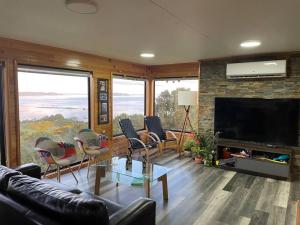 sala de estar con sofá, sillas y TV en Bella casa de campo con panorámica vista al mar, en Dalcahue