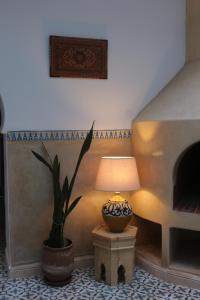 una lámpara sentada en una mesa junto a una maceta en RIAD AMANA, en Essaouira