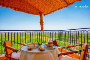 a table on a balcony with a view of a field at Dar Amoudou in Ouarzazate