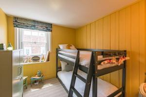 two bunk beds in a room with yellow walls at Noggin in Deal