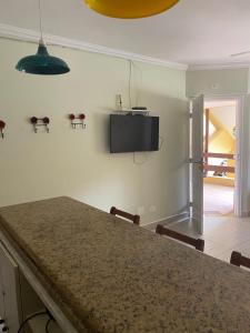 uma cozinha com uma mesa e uma televisão na parede em Flat 102 em Riviera de São Lourenço