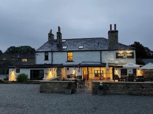 - un grand bâtiment blanc avec une terrasse extérieure dotée de tables dans l'établissement The Black Horse Inn, à Settle