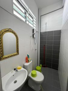 ein Badezimmer mit einem Waschbecken, einem WC und einem Spiegel in der Unterkunft Family Holiday Home With Wifi & Netflix in Sungai Petani