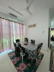 ein Esszimmer mit einem Tisch und Stühlen auf einem Teppich in der Unterkunft Family Holiday Home With Wifi & Netflix in Sungai Petani