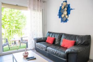 un sofá de cuero negro en una sala de estar con ventana en L'Escale - 2 Chambres balcon à 5 min des plages en Marsella