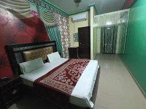 a bedroom with a bed with a red and white blanket at New Hajveri Hotel Lahore in Lahore
