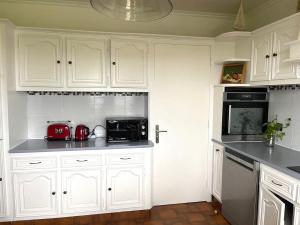 a kitchen with white cabinets and black appliances at Mer, belle vue, emplacement parfait, fonctionnel in Penmarch