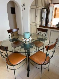 a glass table with four chairs and a kitchen at Villa Maria in Thermisía