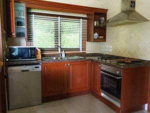 a kitchen with wooden cabinets and a sink and a microwave at Patong 4BD sea view BOOM party&cozy pool villa in Ban Nakhale