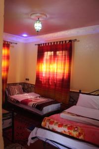 2 Betten in einem Zimmer mit roten Vorhängen in der Unterkunft La Belle étoile in Aït Oussane