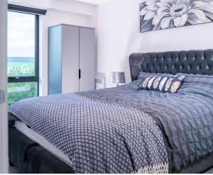 a bedroom with a bed with a blue bedspread and a window at Manchester lovely two bedrooms apartment in Broadheath