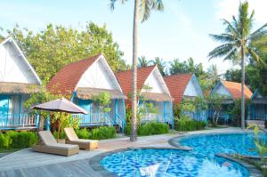 a resort with a swimming pool with chairs and an umbrella at The MG Villa & SPA in Nusa Penida