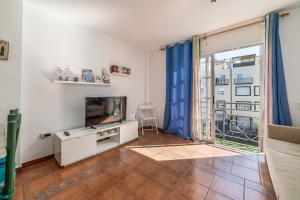 ein Wohnzimmer mit einem TV und einem Balkon in der Unterkunft Callao Salvaje, apartamento a 200 mts de la Playa in Alcalá