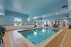 a large swimming pool in a room with chairs and tables at Candlewood Suites Erie, an IHG Hotel in Erie