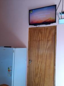 TV de pantalla plana sobre una puerta de madera con nevera en Iguazu...mi lugar en el ? en Puerto Iguazú