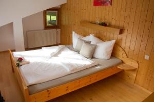 Schlafzimmer mit einem Bett mit weißer Bettwäsche und Kissen in der Unterkunft Ferienhaus Mühlstein in Silbertal