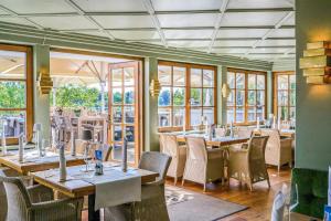 un restaurante con mesas, sillas y ventanas en Gasthof Rabenwirt en Pullach im Isartal