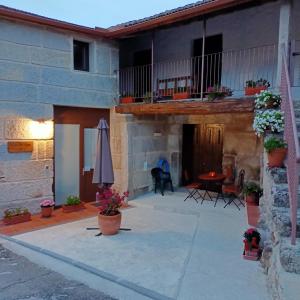 un patio de una casa con una mesa y una sombrilla en Casa da Eira, en Lobios