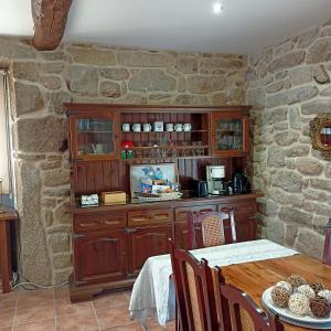 a dining room with a table and a stone wall at Casa da Eira in Lobios