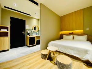 a bedroom with a bed and two tables and a bathroom at 厝True Hub旅店 in Nanwan