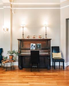 a piano in a living room with two chairs at Princess Anne Boutique Hotel & Breakfast in Asheville