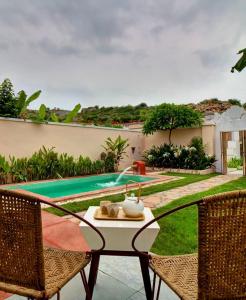 un patio con mesa, sillas y piscina en Parijat Private Pool Villa, en Udaipur