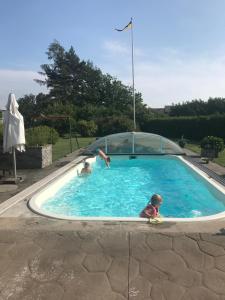 a man diving into a swimming pool with a child in it at Modernt Attefallshus in Ängelholm