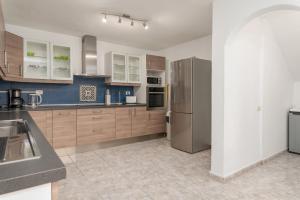 a kitchen with wooden cabinets and a stainless steel refrigerator at Casa Julia in Playa de las Americas +23 photos