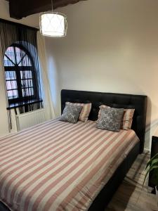 een slaapkamer met een bed met gestreepte lakens en een raam bij Tiltų 5 Apartment in Klaipėda