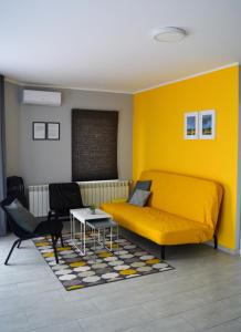 um quarto com uma cama amarela e uma mesa em Apartmani Tika em Golubac