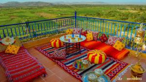 a balcony with a couch and a table with colorful pillows at Dar Amoudou in Ouarzazate