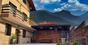 a building with a table and mountains in the background at Къща за гости “Приятели“ in Ovchartsi