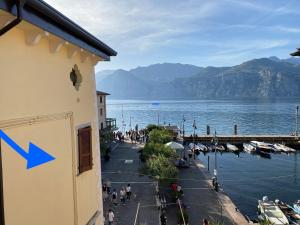 un edificio con una flecha azul junto a un cuerpo de agua en Da Mario Apartments, en Malcesine