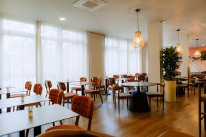 un comedor con mesas, sillas y ventanas en Moods Hotel Dortmund, en Dortmund