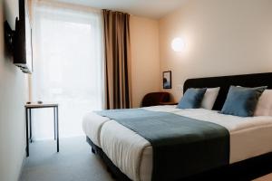 sypialnia z łóżkiem z niebieskimi poduszkami i oknem w obiekcie Moods Hotel Dortmund w Dortmundzie