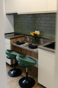 una cocina con barra y 2 taburetes de barra verde en Hotel Vila Discret, en Satu Mare