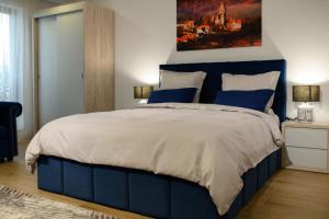 een slaapkamer met een blauw bed en een schilderij aan de muur bij Hotel Vila Discret in Satu Mare