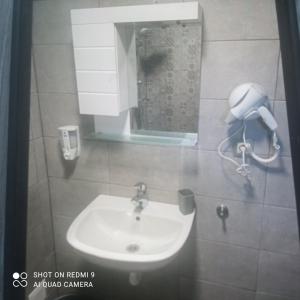 a bathroom with a sink and a phone on the wall at Къща за гости “Приятели“ in Ovchartsi