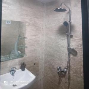 a bathroom with a shower with a sink and a mirror at Къща за гости “Приятели“ in Ovchartsi
