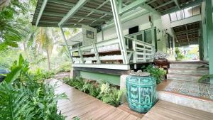 une maison avec un grand vase vert sur une terrasse couverte dans l'établissement Rimsira, à Chumpon
