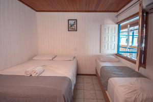 2 camas individuales en una habitación con ventana en Amendoeira Praia Hotel en Morro de São Paulo
