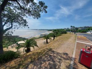 une route avec une valise rouge à côté d'une plage dans l'établissement Solares De Araus, à Colonia del Sacramento