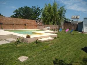 a swimming pool in a yard with two chairs at Complejo SABEJO in San Antonio de Areco