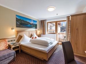 1 dormitorio con 1 cama, 1 silla y 1 ventana en Apart Landhaus Heim, en Mayrhofen