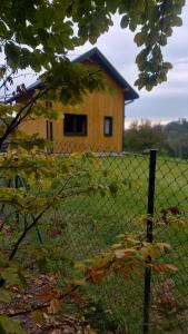 une clôture devant une maison avec un bâtiment dans l'établissement Domek w borówkach, à Tokarnia