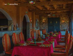 a long table in a room with red tables and chairs at Dar Amoudou in Ouarzazate