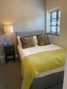a bedroom with a bed with a yellow blanket and a window at The Snug with Jacuzzi -cosy hideout in Coventry