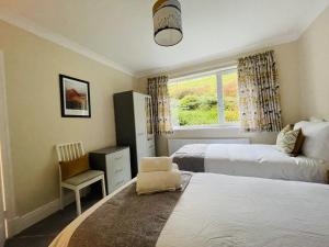 a bedroom with two beds and a chair and a window at Three Peaks in Braithwaite