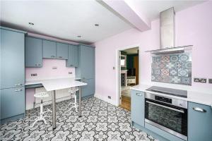 a kitchen with blue cabinets and a table in it at St Mary's Cottage in Boston Spa